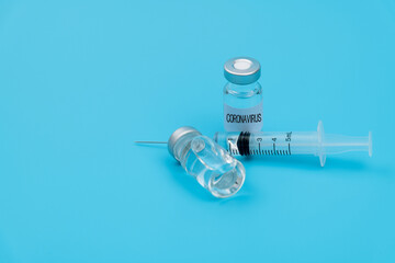 Syringe and coronavirus vaccine on blue background