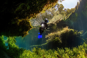 Young woman snorkeling with underwater torch in the river. underwater view.
