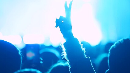 Girl making peace sign with her hand and waving it during live performance in front of stage
