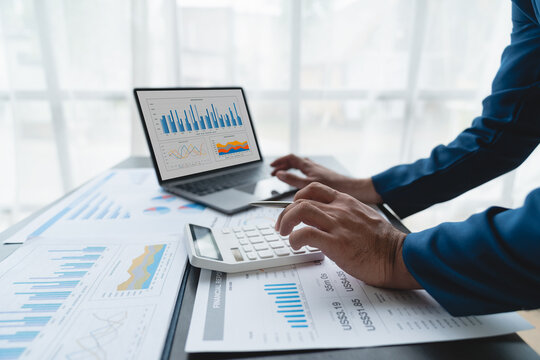 Confident businessman analyzing Calculate and view chart data from documents. financial report graph from laptop computer on office desk.