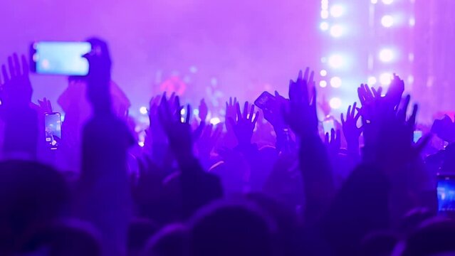 Fans of singer waving their hands and dancing in front of the stage of live performance