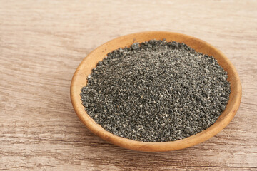 black sesame powder isolated in wood plate table background. pile of black sesame powder in wood plate food background. heap of black sesame powder                      