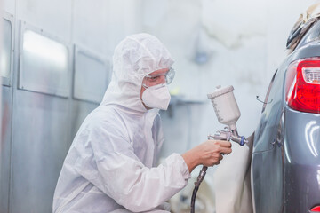 Worker man using spray gun and airbrush and painting a car, Mechanic painting car in chamber,...