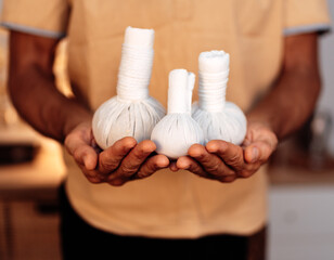panchakarma specialist holding three herbal massage bags in hands, ayurveda healer, master's hands,...