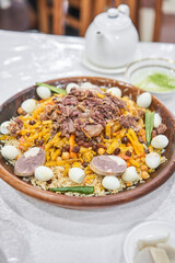 An Uzbek dish called pilaf. Rice with meat, carrots, onions, eggs and kazy in a plate of astau on the table. A traditional Uzbek dish called pilaf. A portion for three people.