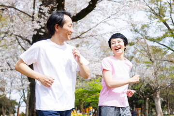 公園でジョギングするスポーツウェアの成熟した日本のカップル