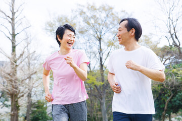 公園でジョギングするスポーツウェアの成熟した日本のカップル