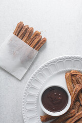 Top view of cinnamon sugar covered churros in a paper bag with chocolate sauce in a ramekin, Fried churros in bakery bag