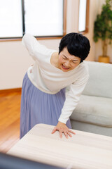 家で腰痛に苦しんでいる成熟した日本人女性 - obrazy, fototapety, plakaty