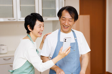 キッチンに携帯電話を持つ成熟した日本のカップル