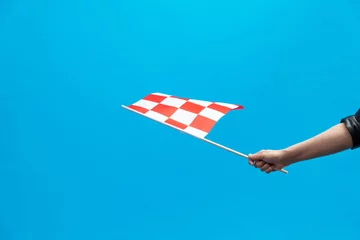 Stof per meter Human hand waving checkered flag on blue background © xy