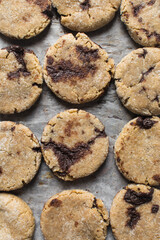 Homemade chocolate stuffed cookies on a parchment lined baking sheet, vanilla and chocolate cookies, thick vanilla cookies with a chocolate filling