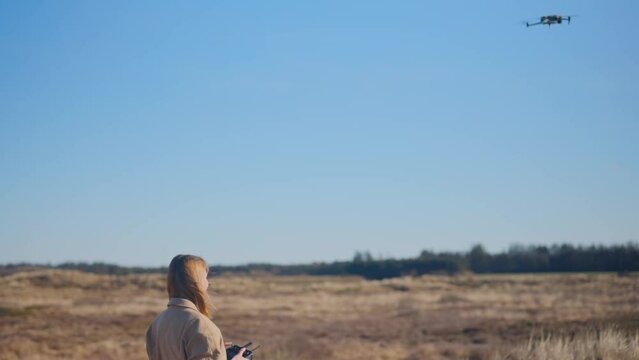 a girl flying a drone in a field