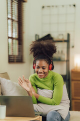 Focused young African female college student working on a laptop on living room.