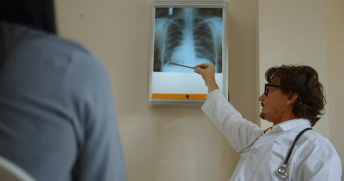 A medical professional is explaining the injury on the x-ray film to the patient.