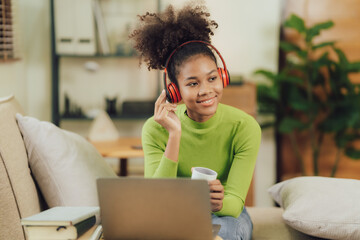Focused young African female college student working on a laptop on living room.