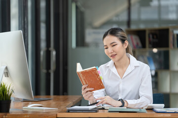 Business concept, Woman entrepreneur reading a book while working in a coworking space office.
