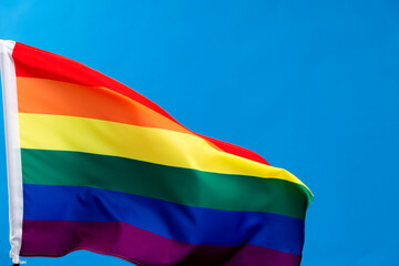Rainbow flag waving on blue background