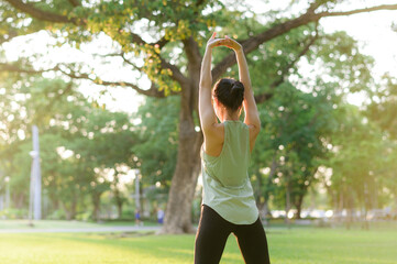 Female jogger. Fit young Asian woman with green sportswear stretching muscle in park before running and enjoying a healthy outdoor. Fitness runner girl in public park. Wellness being concept - obrazy, fototapety, plakaty