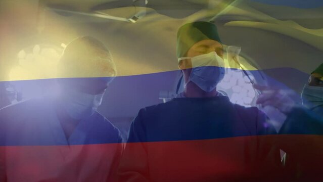 Animation of waving colombia flag against team of surgeons performing surgery at hospital