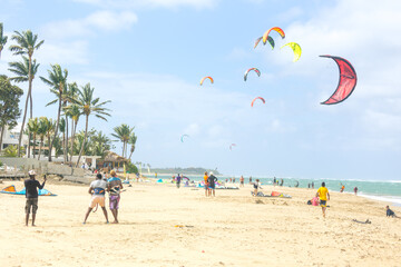 Crowd of active sporty people enjoying kitesurfing holidays and activities on perfect sunny day on Cabarete tropical sandy beach in Dominican Republic - obrazy, fototapety, plakaty