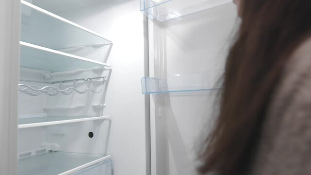 What's for dinner? Pretty brunette opens empty fridge and closes in disappointment
