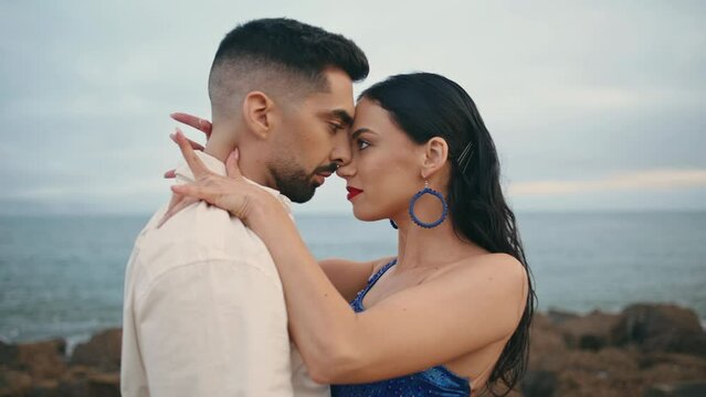 Hot passionate latino performers dancing together on cloudy ocean coast close up