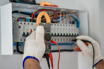 An electrical engineer is working on a home electrical control panel system and checking the...