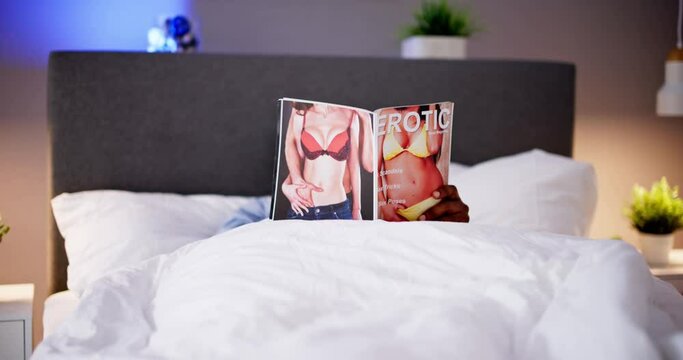 Man Lying On Bed Reading Erotic Magazine