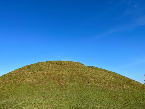 Landscape view of green meadow hill with clear blue sky on the background.