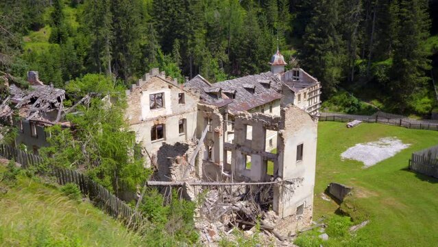 Ruins of an abandoned 19th century sanatorium with roof caved in, in a forest area. Wide tracking shot.