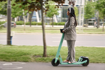 Chinese business woman riding on push scooter and listening to music © gpointstudio