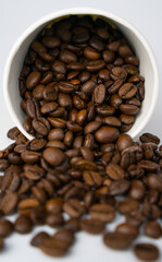 Coffee beans spilled out of a paper cup. Close-up. Selective focus.