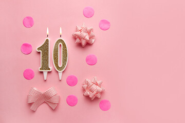 Number 10 on pastel pink background with festive decor. Happy birthday candles. The concept of celebrating a birthday, anniversary, important date, holiday. Copy space. Banner