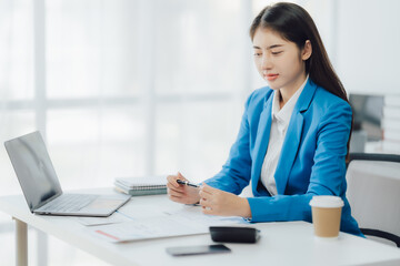 Young charming businesswoman sitting at her desk with laptop computer on the table.