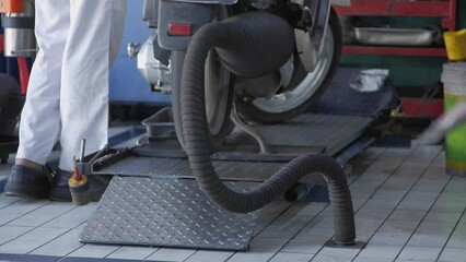 Motorcycle service officers check the engine and exhaust gases using a special tool mounted on the muffler