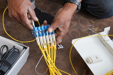 Technician installing fiber optic cable in junction box and testing cables with optical power meter 