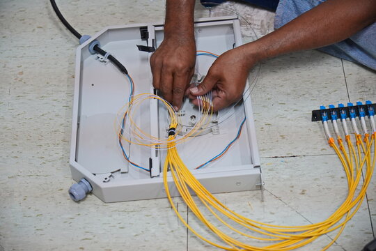 Technician installing fiber optic cable in junction box