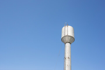 a water tower providing the village with clean drinking water against a blue sky
