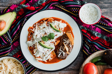 Mexican chilaquiles food with spicy red sauce, chicken and avocado traditional breakfast in Mexico Latin America