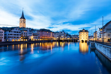Fototapeta na wymiar Panorama landscape along Limmat river in twilight sunset with background.Blue sky in the evening.Winter season in Switzerland with reflection on Limmat river.Colorful light cityscape.Clock and bridge.
