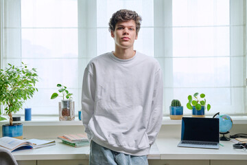 Portrait of handsome guy 19 years old looking at camera in home interior