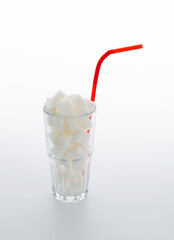 Glass cup full of sugar cubes on white background