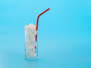 Glass cup full of sugar cubes on blue background