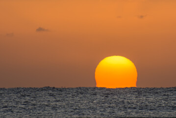amazing sunrise with a distorted orange sun at the horizon from the red sea in egypt large