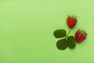 Strawberries with leaves on color background, top view