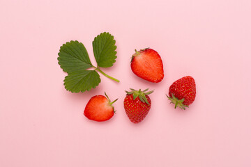 Strawberries with leaves on color background, top view