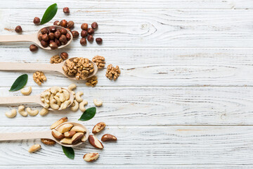 mixed nuts in white wooden spoon. Mix of various nuts on colored background. pistachios, cashews, walnuts, hazelnuts, peanuts and brazil nuts