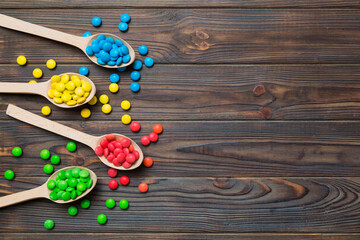 delicious colorful sweet candies on spoon on colored background . Confectionery decor top view with copy space