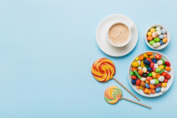 Coffee cup with chocolates and colored candy. Top view on table background with copy space